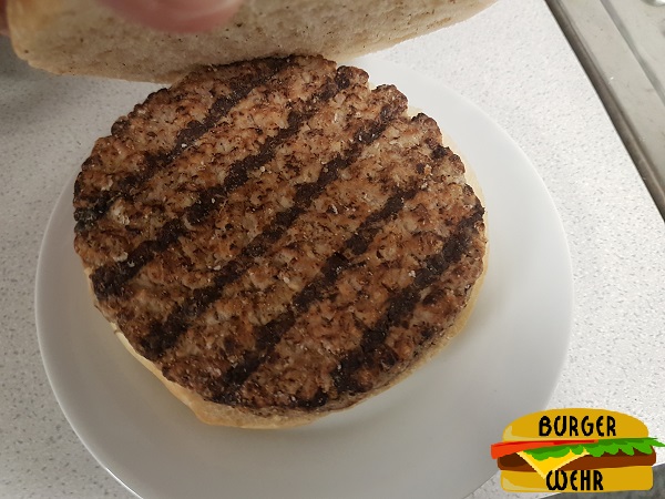 Ein aufgeklappter Mikrowellen Cheeseburger mit Brandstreifen auf dem Fleisch
